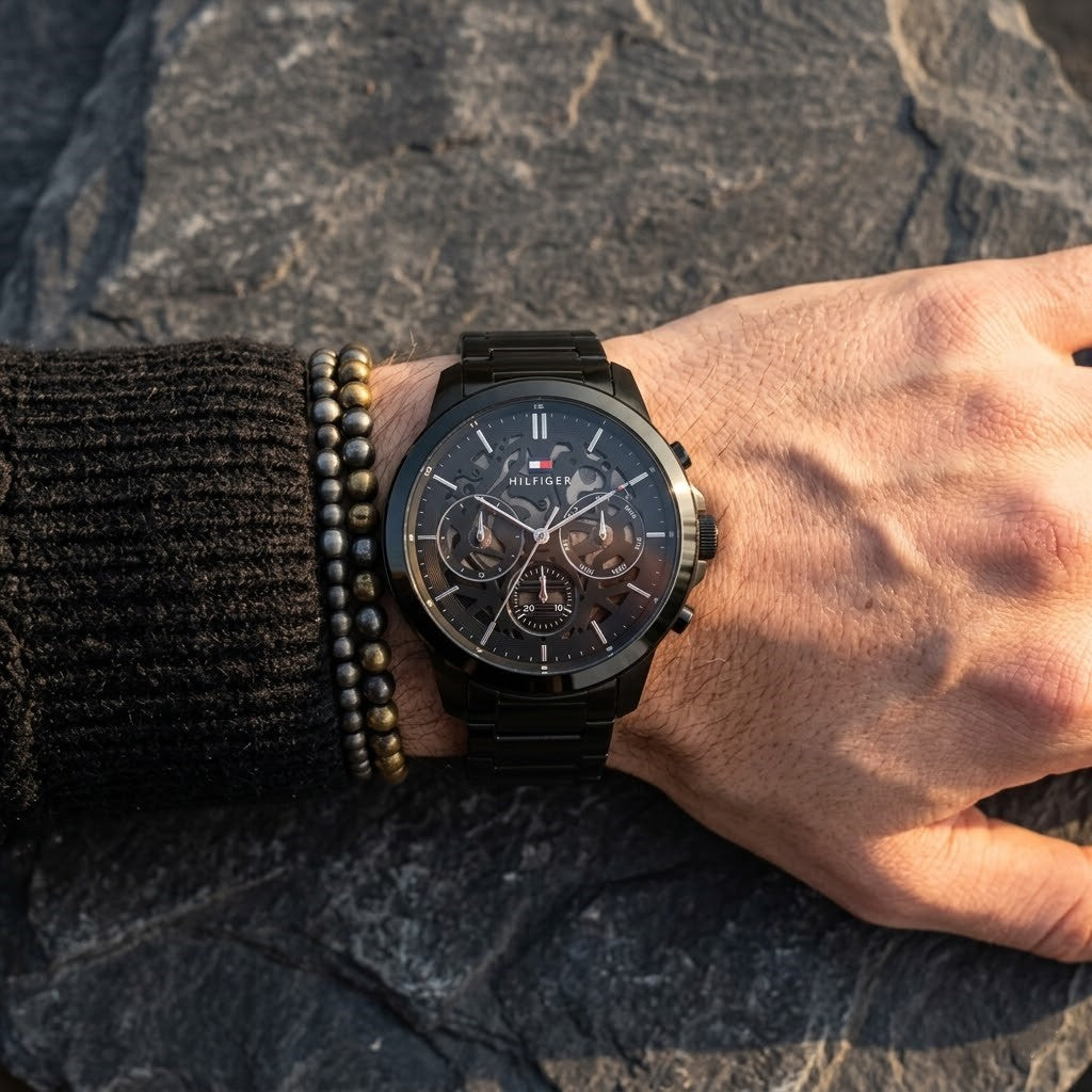 Close up of Tommy Hilfiger Henry 1710685 men's quartz battery watch on wrist showing stealth black skeleton dial and black link bracelet