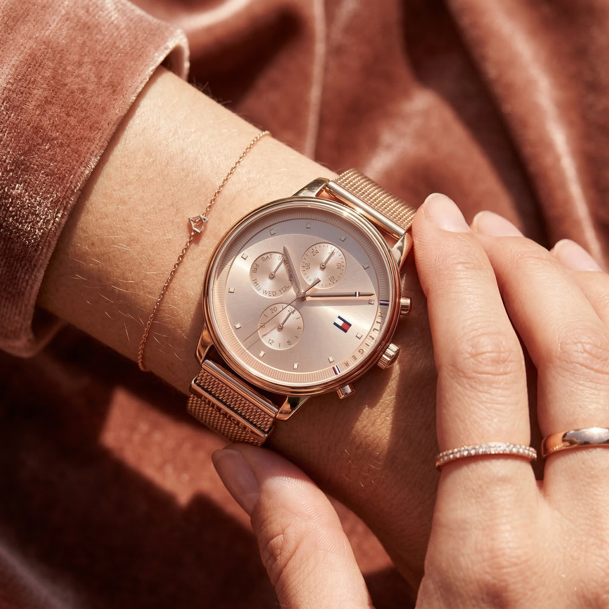 Close up of Tommy Hilfiger 1781907 women's quartz battery watch on wrist showing rose gold dial and mesh bracelet