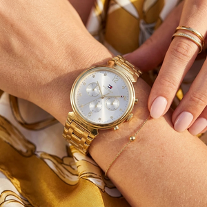 Close up of Tommy Hilfiger Ivy 1782344 women's quartz battery watch on wrist showing silver sunray dial and gold metal bracelet