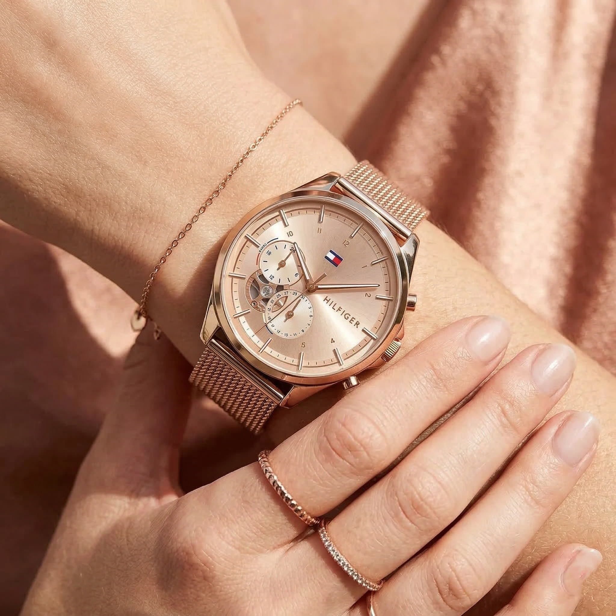 Close up of Tommy Hilfiger Quinn 1782486 women's quartz battery watch on wrist showing rose gold sunray dial and rose gold mesh bracelet