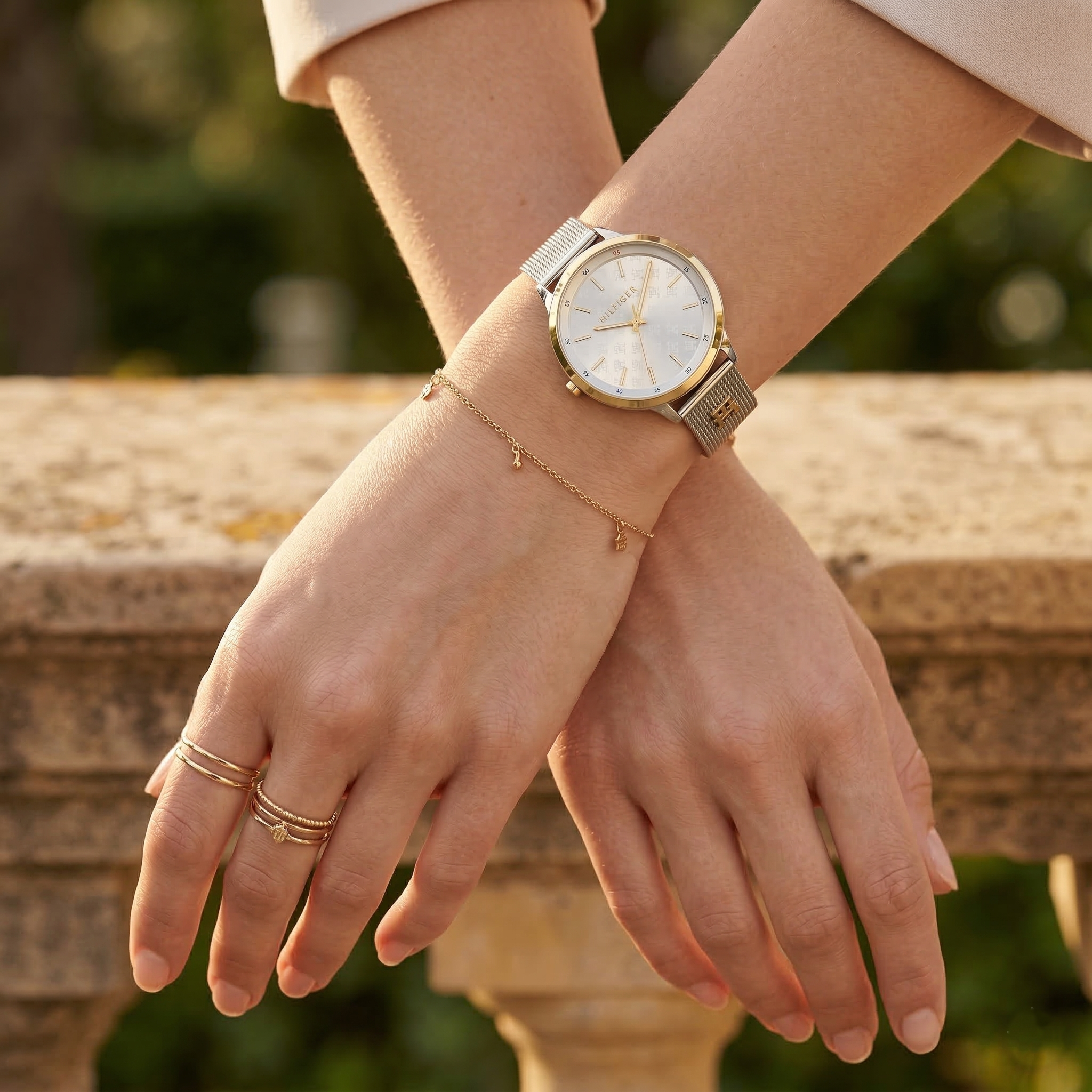 Elegant woman wearing Tommy Hilfiger 1782586 women's quartz battery watch with two-tone silver-gold case and luxury mesh strap