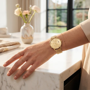 Close up of Tommy Hilfiger 1782606 women's quartz battery watch on wrist showing gold floral dial and luxury gold mesh bracelet