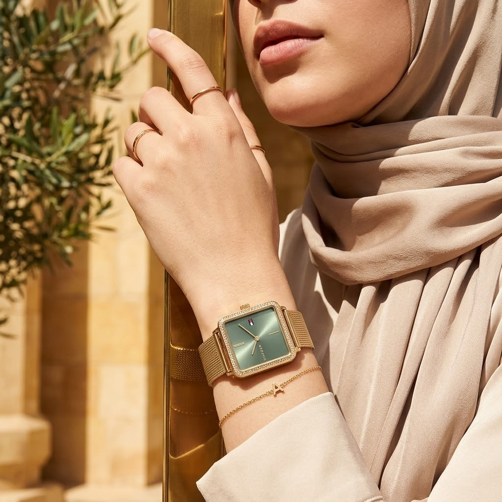 Elegant woman wearing Tommy Hilfiger Tea 1782791 women's quartz battery watch with gold case and luxury square mesh strap