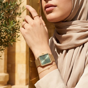Elegant woman wearing Tommy Hilfiger Tea 1782791 women's quartz battery watch with gold case and luxury square mesh strap