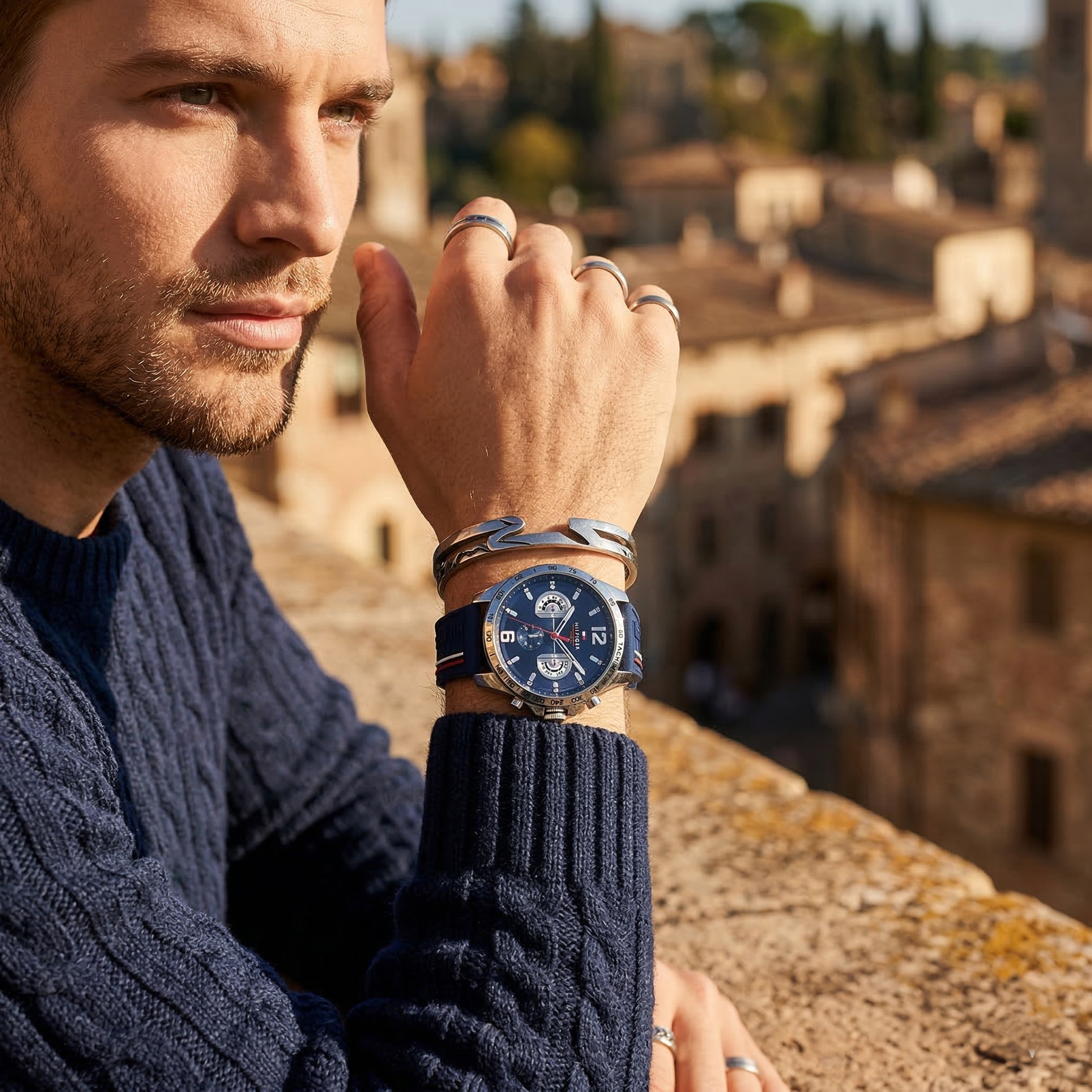 Elegant man wearing Tommy Hilfiger Decker 1791476 men's quartz battery watch with silver-tone case and sporty blue logo strap