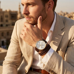 Man in a beige suit with a wristwatch, outdoors with blurred background