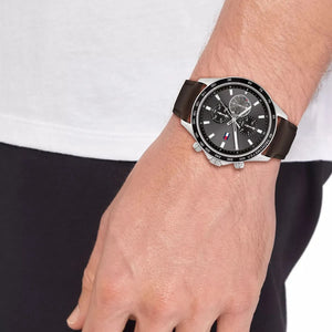 Close up of Tommy Hilfiger Miles 1792015 men's quartz battery watch on wrist showing gray sunray dial and brown leather strap