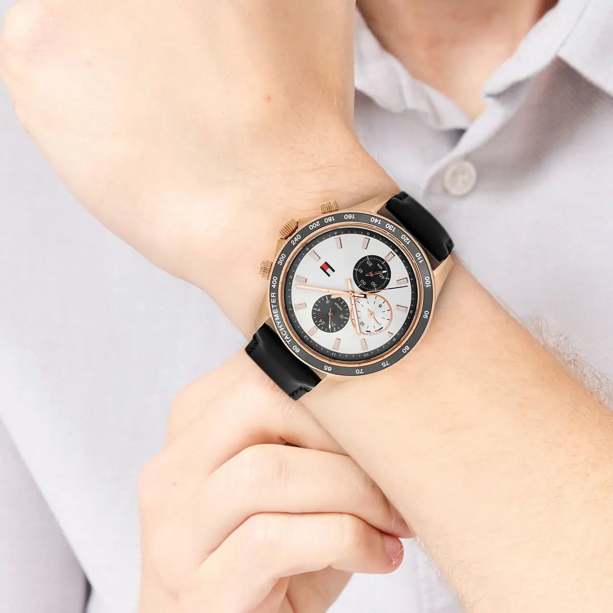 Close up of Tommy Hilfiger Miles 1792016 men's quartz battery watch on wrist showing white sunray dial and black leather strap