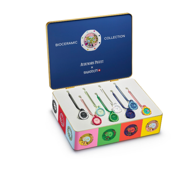 An open presentation box from the Bioceramic Collection x Swatch x Audemars Piguet, displaying multiple colorful watch face components and small watch pieces arranged in a white tray. The box lid is dark blue with gold trim and features the brand names 'BIOCERAMIC COLLECTION', 'AUDEMARS PIGUET', and 'swatch' printed on it.