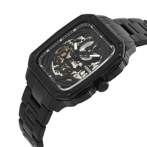 A black skeleton watch with a rectangular case and matching black link bracelet, shown on a plain white background. The watch face is partially transparent, revealing the inner mechanical gears and movement.
