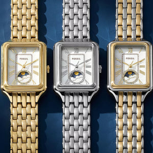 Three Fossil watches with different colored metal bands on a blue background