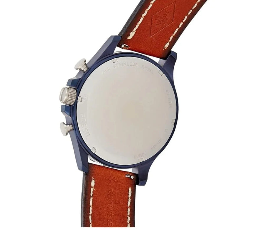 Close-up of the back of a wristwatch with a blue case, silver screw details, and a brown leather strap with white stitching on a white background.