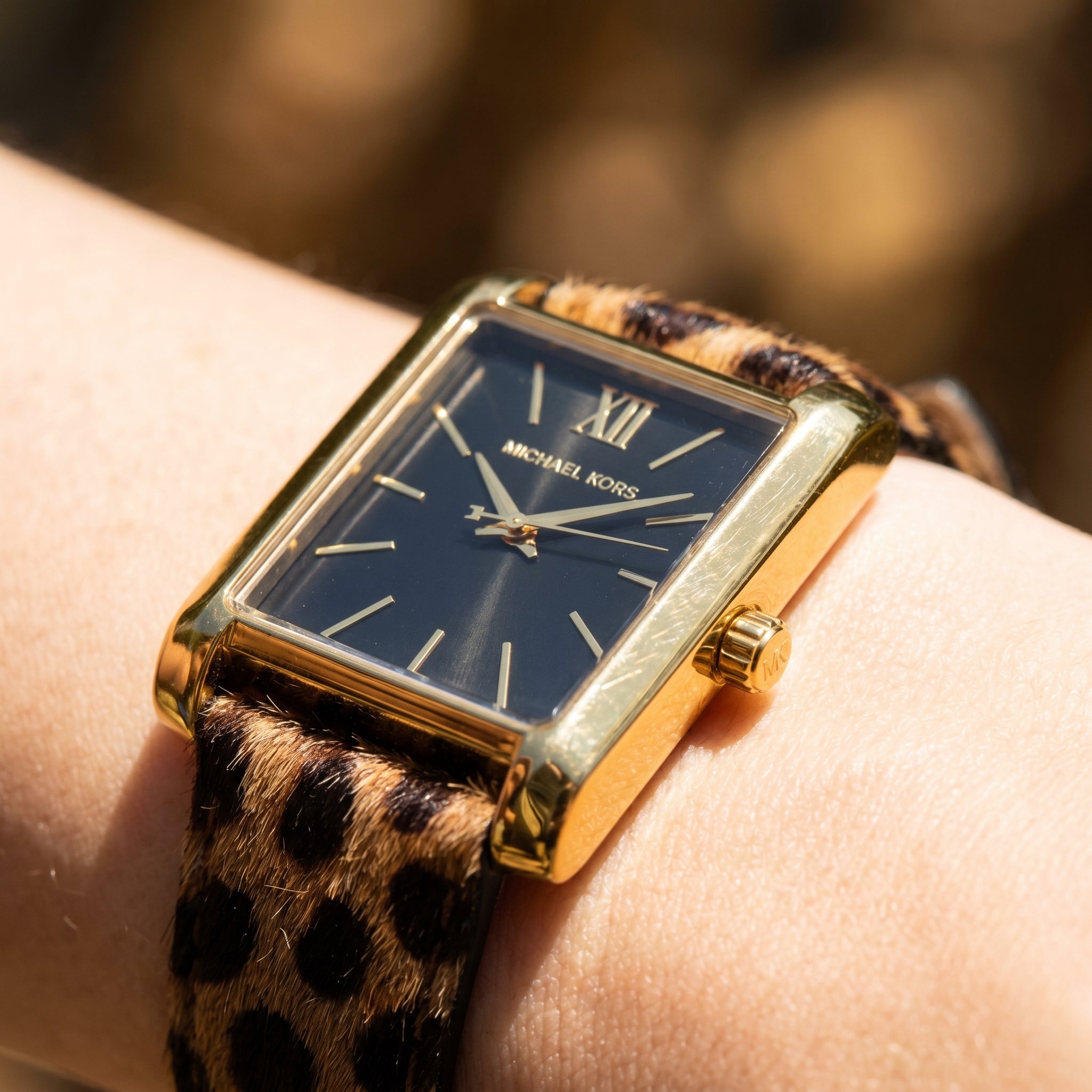 Close up shot of Michael Kors MKo1115 on wrist showing black dial and gold-tone Roman numerals