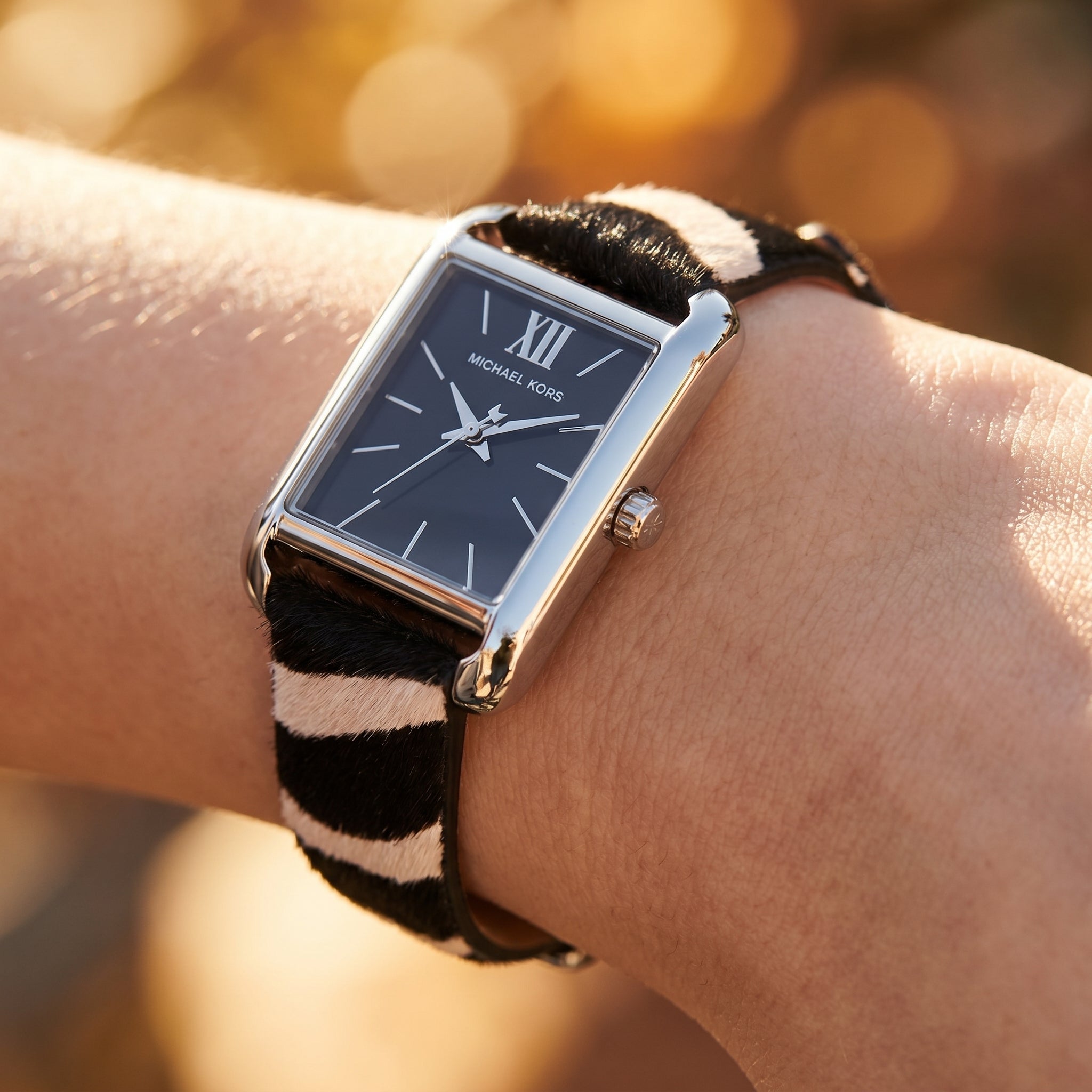 Close up shot of Michael Kors MKo1147 on wrist showing black dial and silver-tone Roman numerals