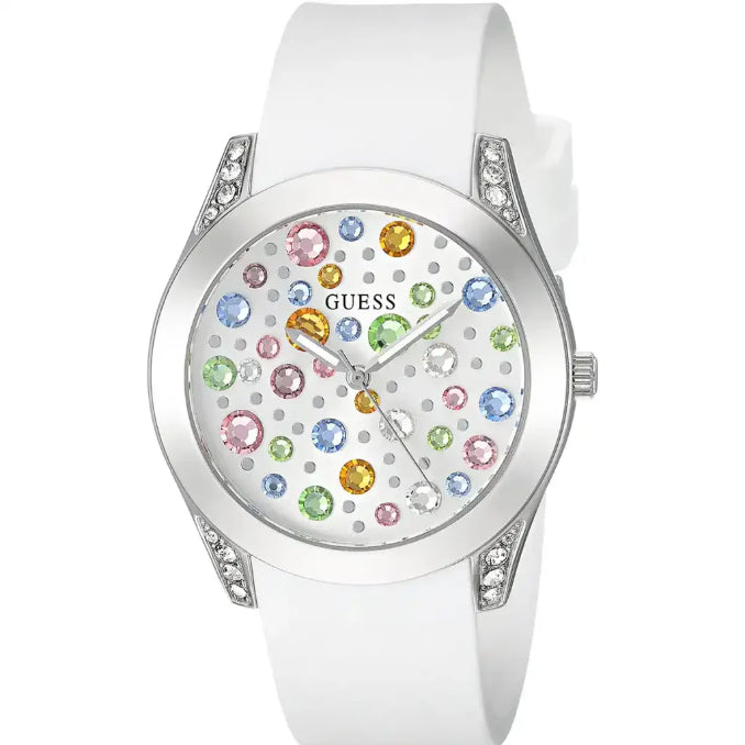 A white Guess watch with a white silicone strap, a silver-tone case accented with clear crystals, and a white dial decorated with colorful gem-like hour markers.