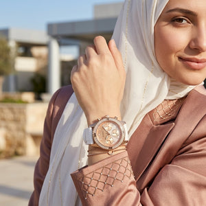 Elegant woman wearing Guess Confetti W1098L5 women's multi-function rose gold watch with pure white rubber strap, adding distinctive casual luxury style