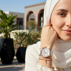Elegant woman wearing Guess Solar W1135L1 women's quartz battery multi-function rose gold watch with pure white rubber strap, adding distinctive casual luxury style