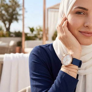 Elegant woman wearing Guess Solar W1135L3 women's quartz battery multi-function gold watch with royal blue rubber strap, adding distinctive casual luxury style
