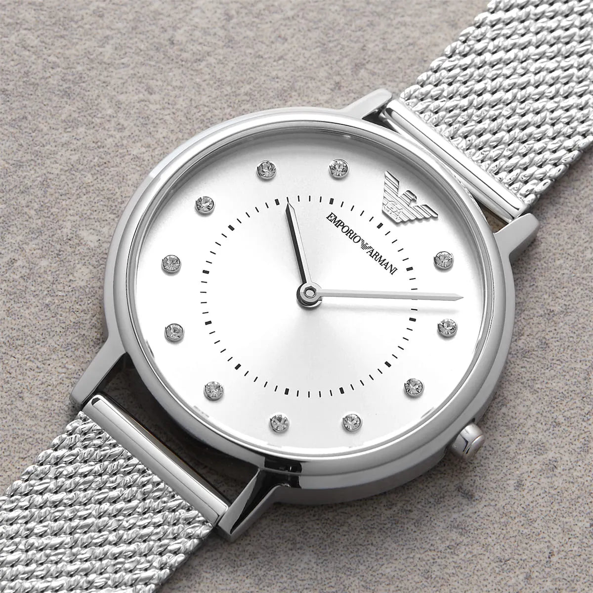 Silver Emporio Armani watch with a textured strap on a gray background
