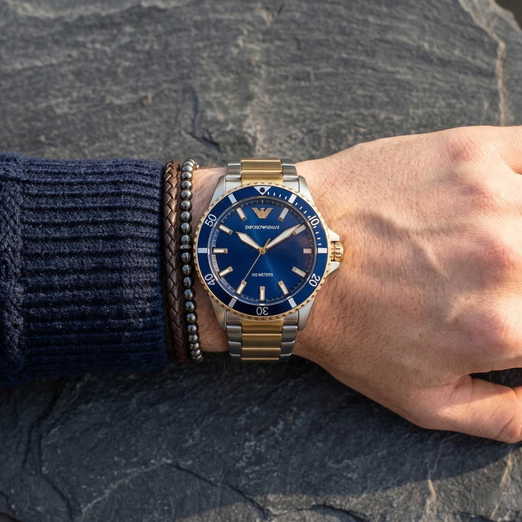 Elegant man wearing Emporio Armani World Explorer AR11682 men's quartz battery watch with two-tone case and luxury diver style