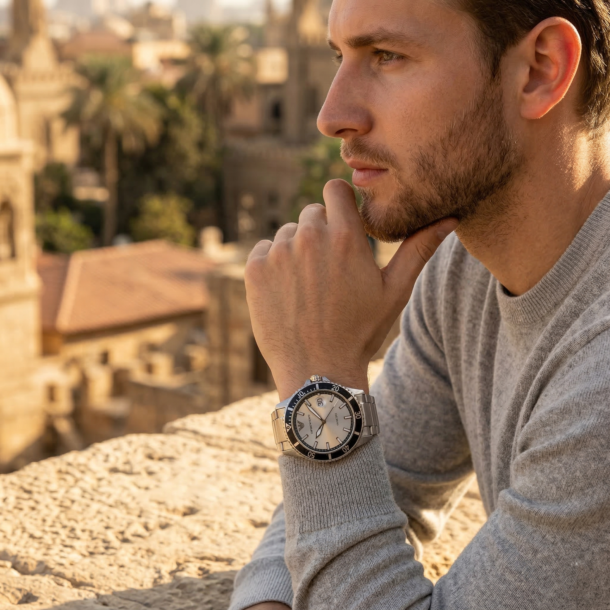 Elegant man wearing Emporio Armani World Explorer AR11683 men's quartz battery watch with silver-tone case and luxury diver style