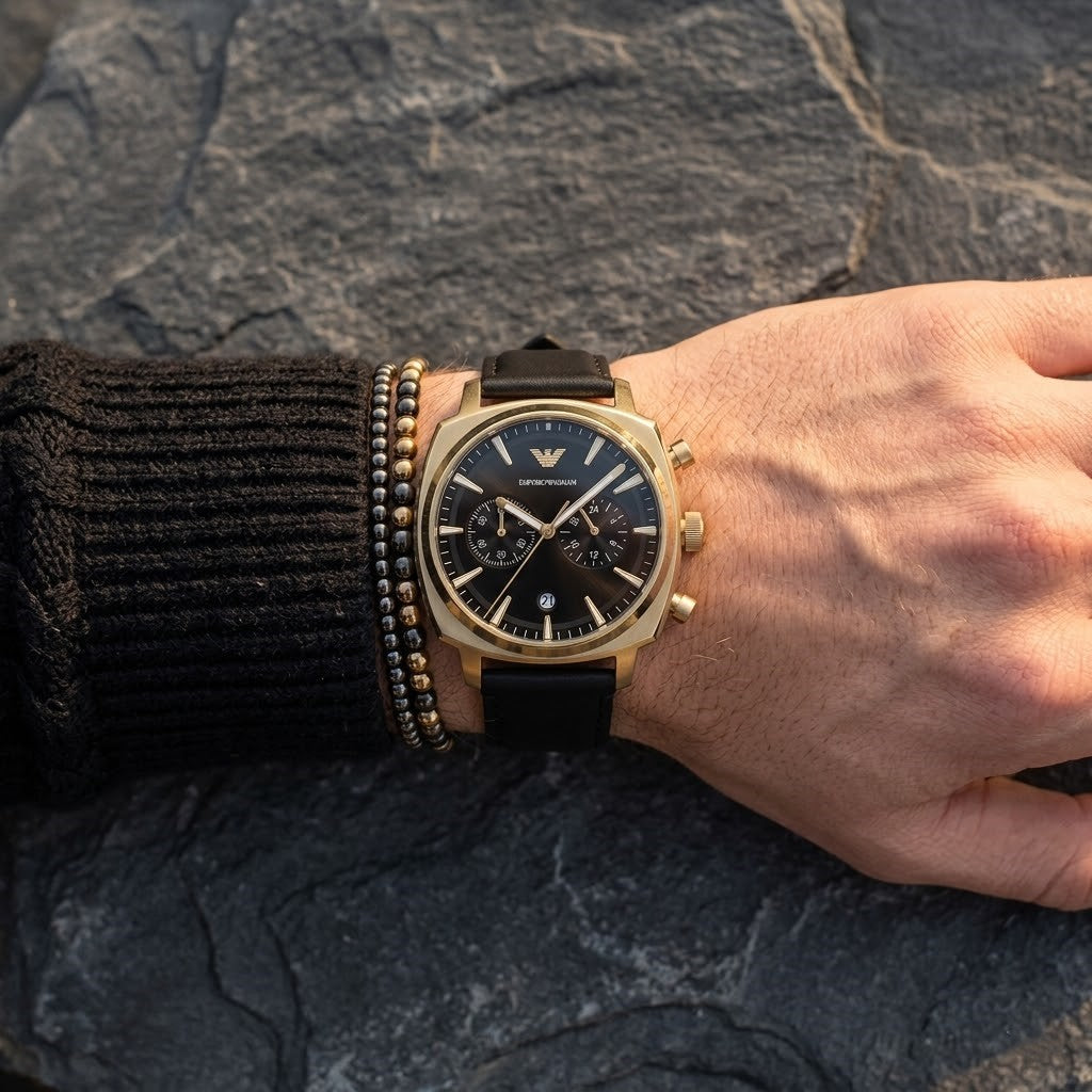 Close up of Emporio Armani Carlo AR11690 men's quartz battery watch on wrist showing deep black dial and luxury gold eagle logo