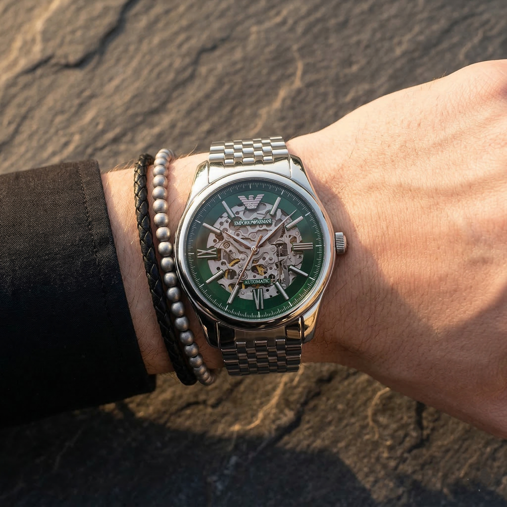 Close up of Emporio Armani Antonio AR60091 men's automatic watch on wrist showing intricate green skeleton dial and silver metal bracelet