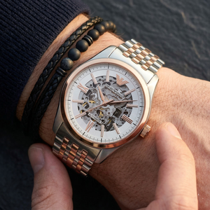 Close up of Emporio Armani Antonio AR60092 men's automatic watch on wrist showing intricate white skeleton dial and two-tone metal bracelet