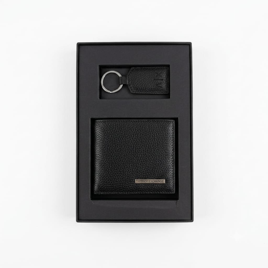 Live smartphone photograph of the Armani Exchange AX mirror original 2-piece gift set showcasing the black leather wallet with silver logo and matching metal keychain inside the custom black and red box