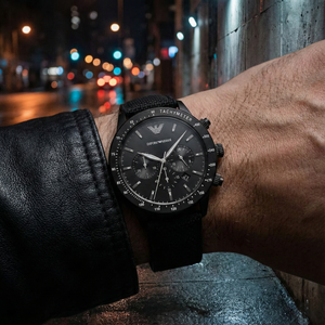Man wearing Emporio Armani AR11453 all-black watch in a dark urban setting