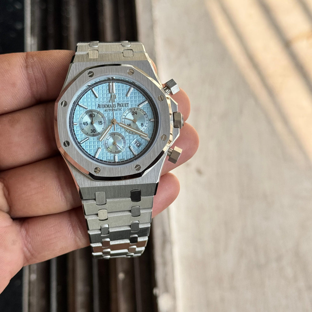 Audemars Piguet Royal Oak men's chronograph watch, light blue dial, silver stainless steel bracelet – in-hand tilted view
