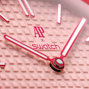 Close-up of a pink Swatch watch face with brand logo