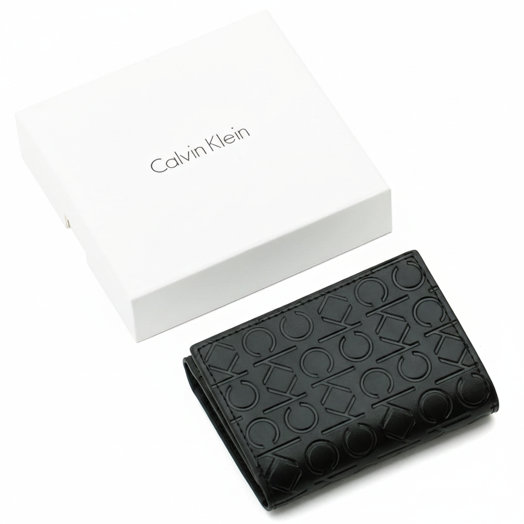 A closed Calvin Klein men's black leather flap wallet featuring an all-over embossed CK logo pattern, placed next to its matching closed white branded gift box