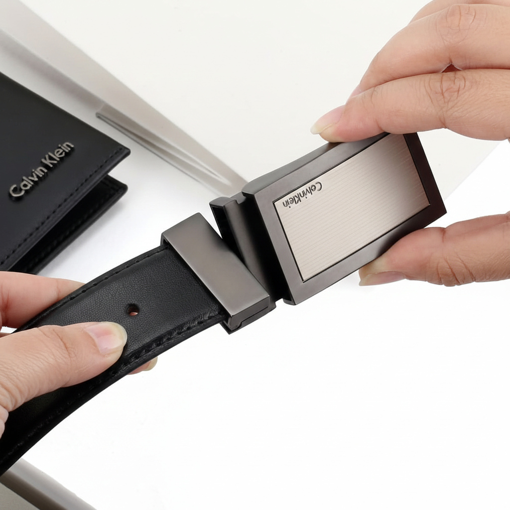 Close-up of a Calvin Klein black smooth leather belt highlighting the sleek minimalist brushed metal buckle with engraved logo
