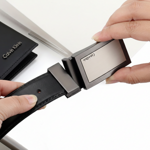 Close-up of a Calvin Klein black smooth leather belt highlighting the sleek minimalist brushed metal buckle with engraved logo