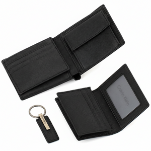 Angled top-down view of a Calvin Klein 3-piece gift set: black saffiano leather bifold wallet, matching card holder, and premium leather keychain on a white background