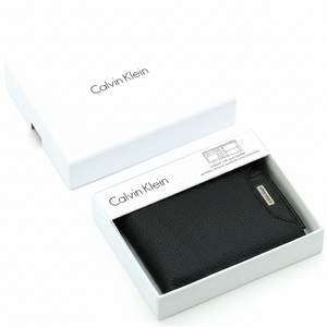 Top-down view of a Calvin Klein men's black pebbled leather wallet displayed securely inside its original white branded gift box