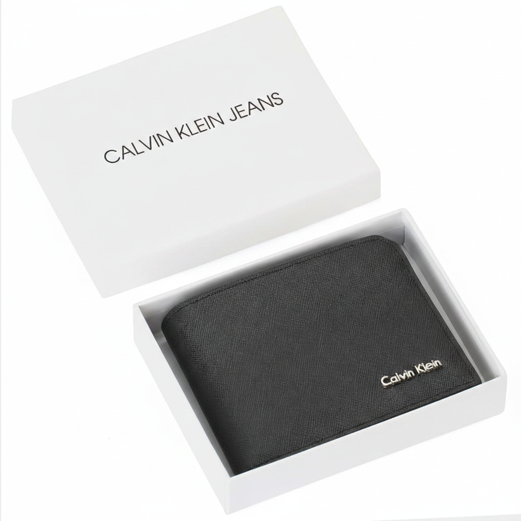 Top-down view of a Calvin Klein men's black saffiano leather wallet with a silver metal logo, presented inside its original white gift box next to a matching shopping bag