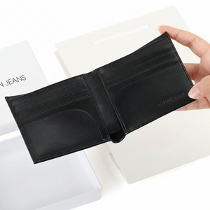 Fully open interior view of a Calvin Klein men's black smooth leather wallet showcasing multiple card slots, debossed branding, and a fold-out passcase flap with a clear ID window