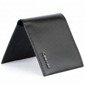 Straight-on front view of a closed Calvin Klein men's black smooth leather bifold wallet featuring a small silver metal logo hardware on the corner