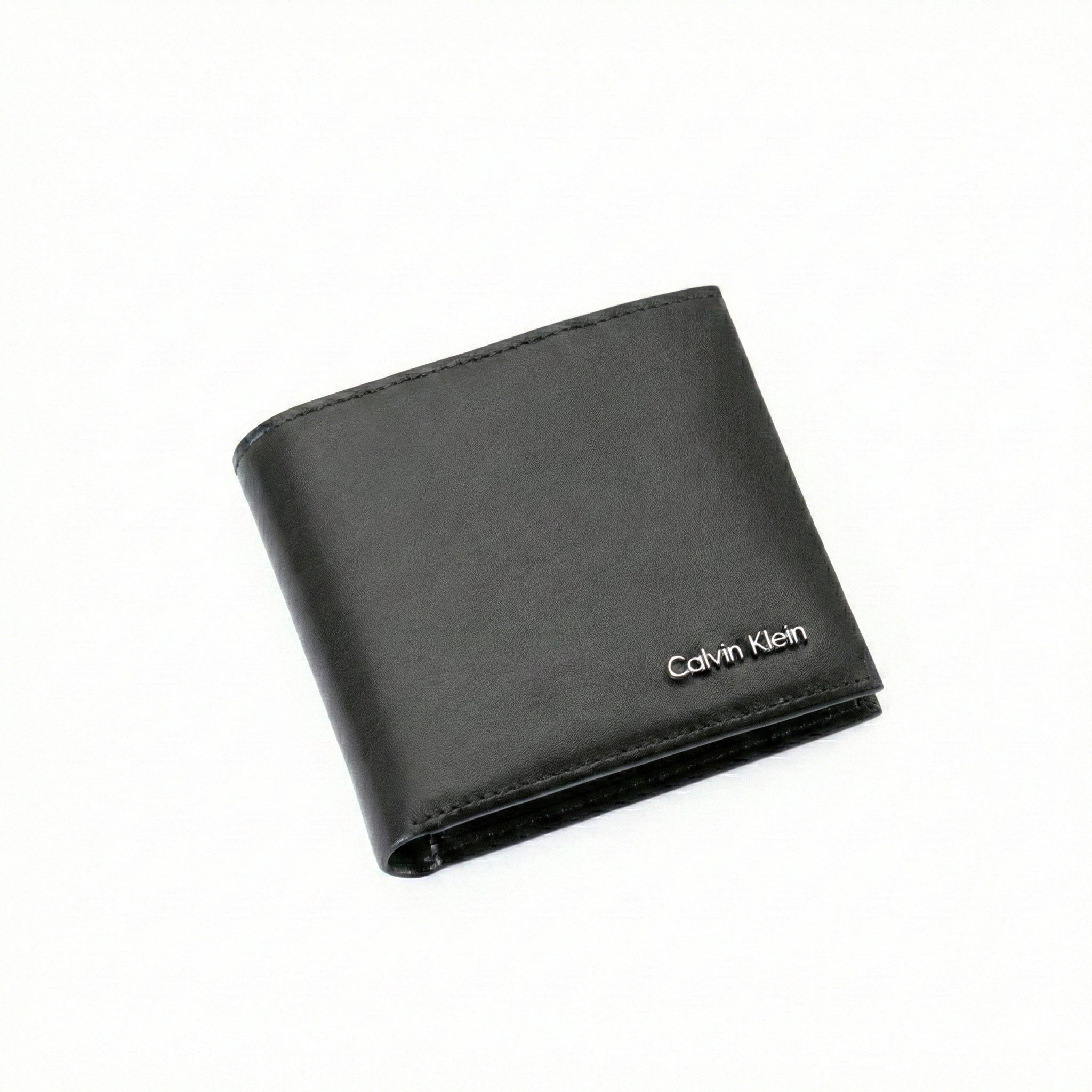 Angled high-perspective view of a closed Calvin Klein men's black smooth leather wallet highlighting the elegant minimalist design and silver metal logo hardware