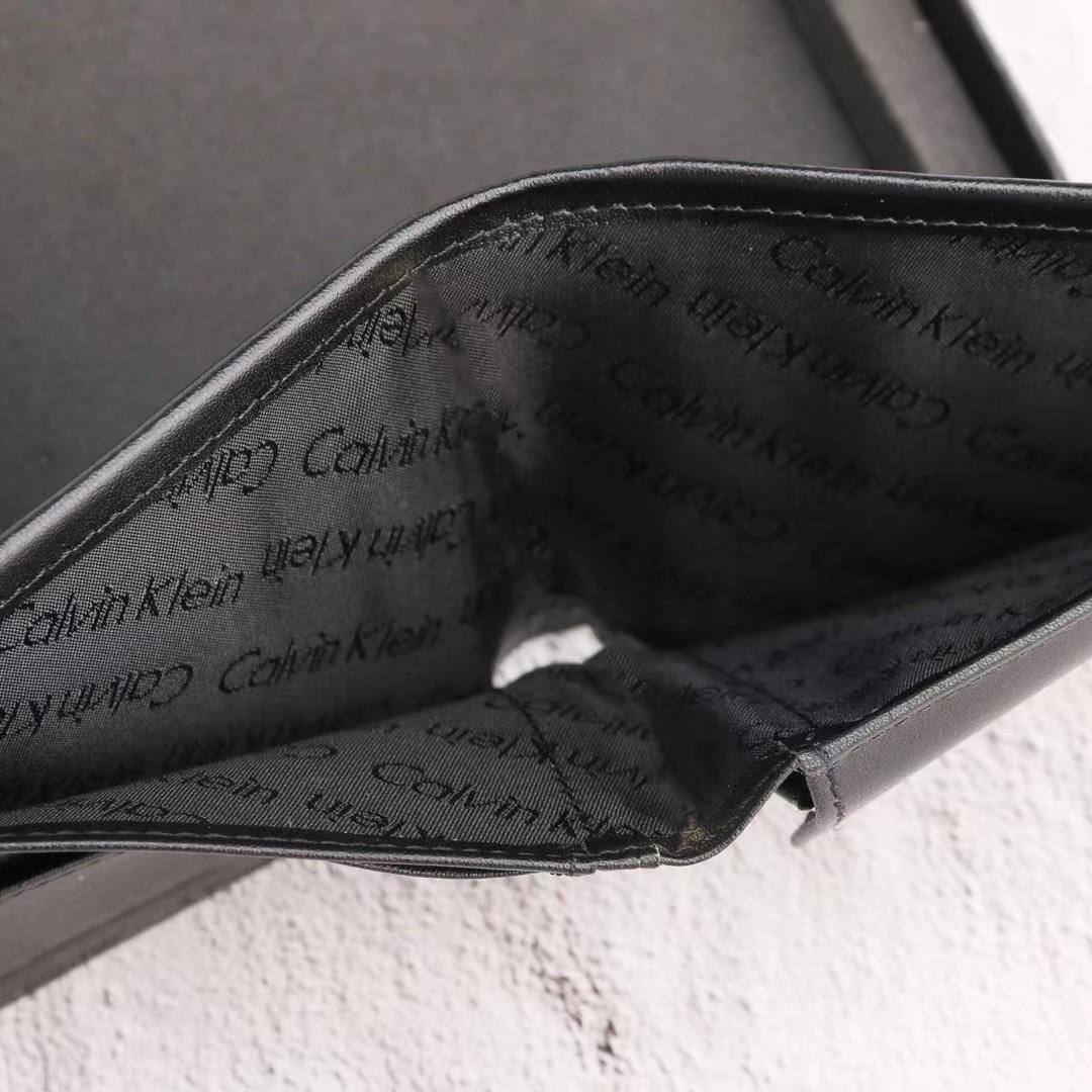 Close-up of a black Calvin Klein wallet with brand name pattern.