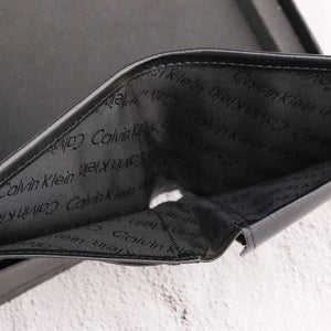 Close-up of a black Calvin Klein wallet with brand name pattern.