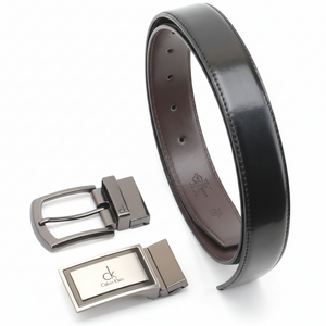 Angled perspective of a rolled Calvin Klein black leather belt and its two interchangeable buckles, highlighting the high-quality craftsmanship and polished metal finish