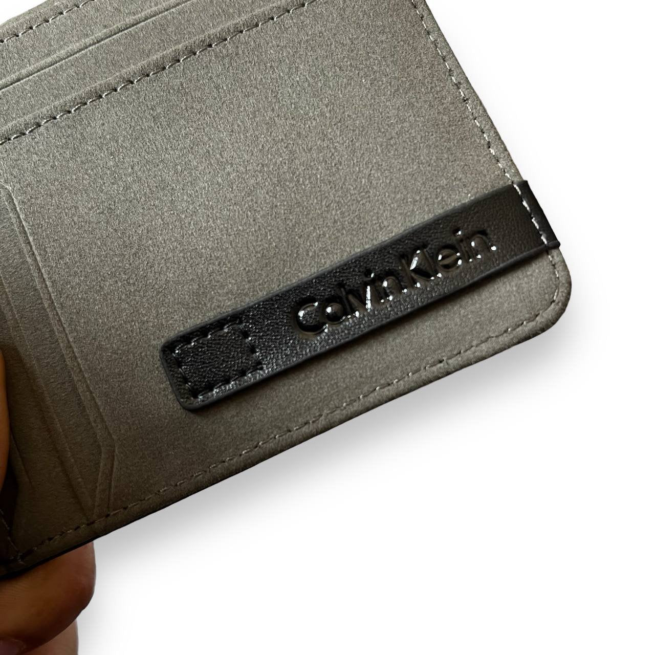 Interior view of an open black Calvin Klein men's bifold wallet showing multiple card slots.