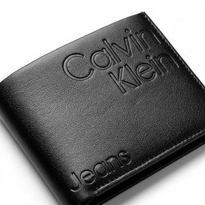 Macro close-up studio shot focusing on the debossed Calvin Klein Jeans logo text over the black smooth genuine leather surface