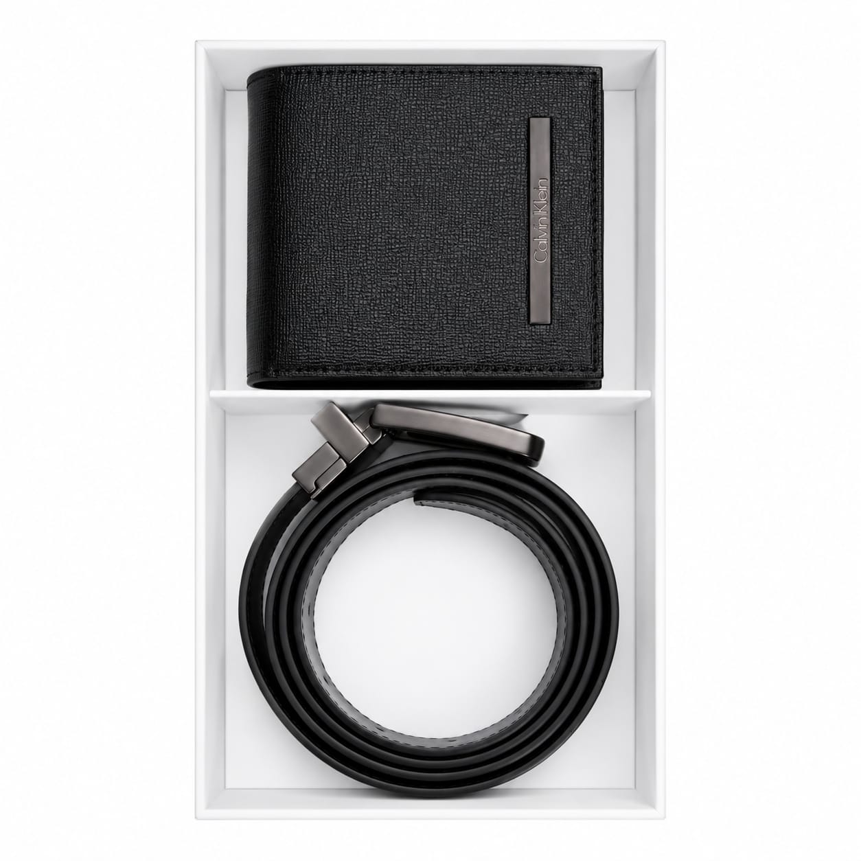 Live smartphone photograph of the Calvin Klein mirror original 2-piece gift set showcasing the black leather wallet with round silver logo and rolled reversible belt inside the custom white box