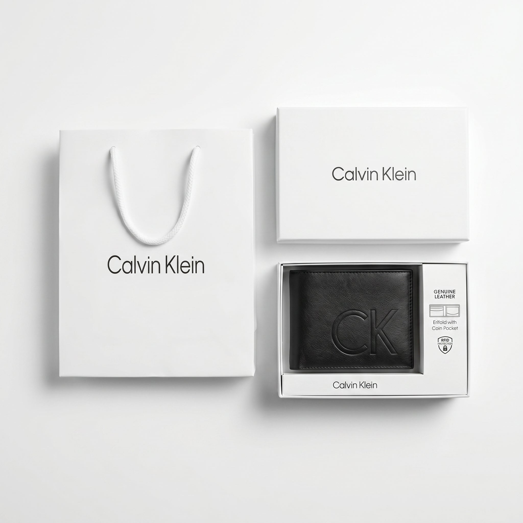 Full premium packaging presentation of the Calvin Klein mirror original smooth black leather bifold wallet alongside its white gift box and matching shopping bag