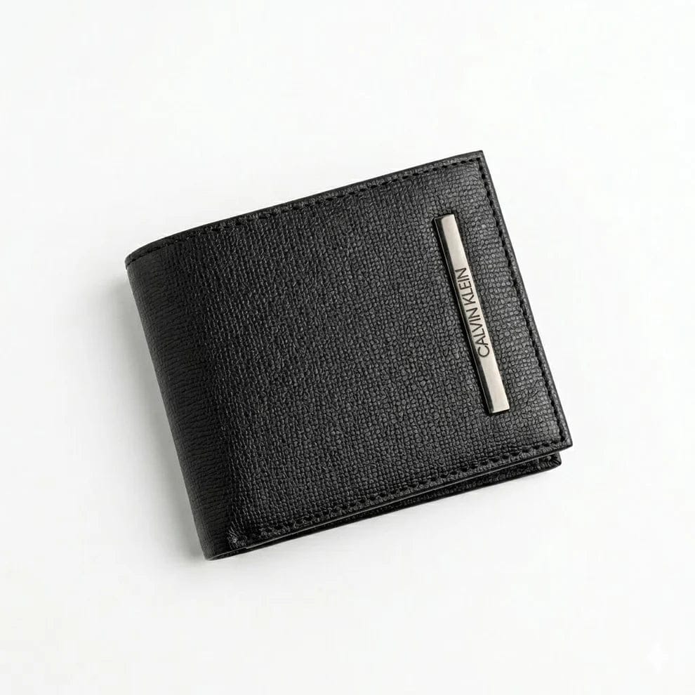 Live front view smartphone photograph of the Calvin Klein smooth black leather bifold wallet highlighting the round silver metal CK hardware logo corner accent