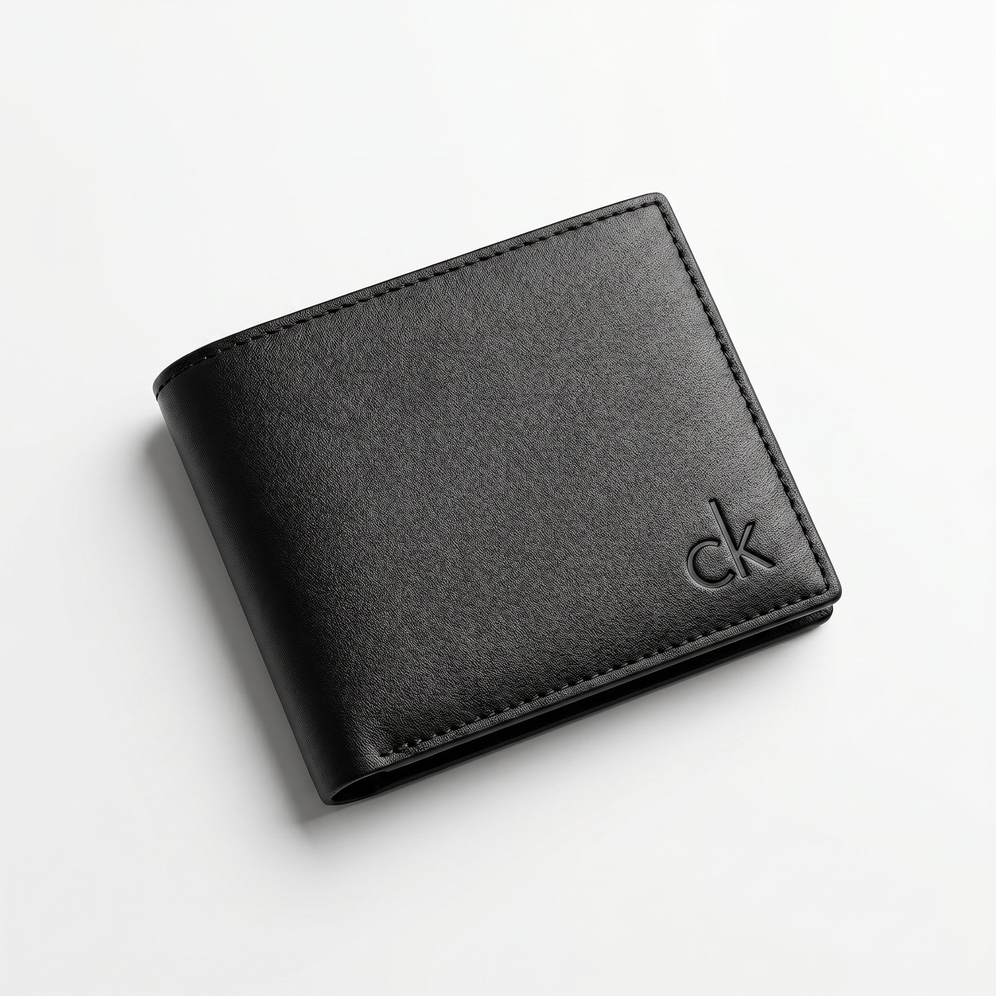 Macro close-up studio shot focusing on the small debossed ck logo accent over the black smooth genuine leather surface